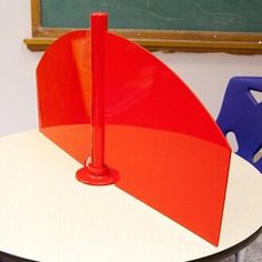 an orange and red umbrella sitting on top of a table in front of a chalkboard