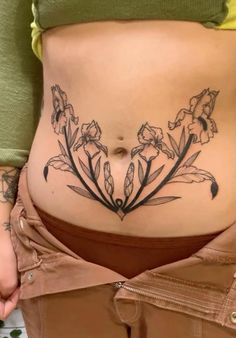 a woman's stomach with flowers and leaves tattooed on the side by her belly