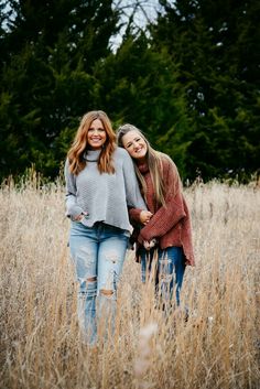 two women standing in tall grass with trees in the background