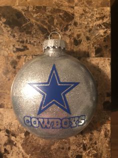 a silver ornament with a blue star on the front and cowboys written on it