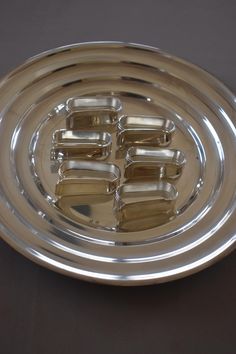 a silver plate with six pieces of metal on it's side and four smaller ones in the middle