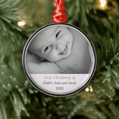 a baby's first christmas ornament hanging from a tree