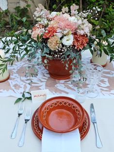 a table set with plates, silverware and flowers