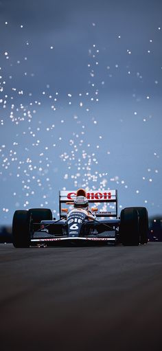 a race car driving down a track with the sky in the back ground behind it