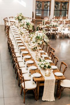 a long table with white flowers and greenery is set up for a wedding reception