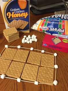 crackers and marshmallows are arranged on a table next to a bag of honey