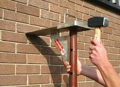 a man is holding a hammer over a brick wall