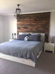 a bedroom with a bed, nightstands and a wooden headboard on the wall