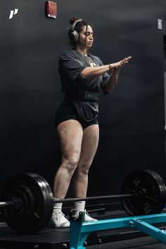 a woman is doing squats on a bench with headphones in her ears and holding a barbell