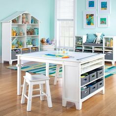 a child's play table and chairs in a room with blue walls, hardwood floors and white furniture