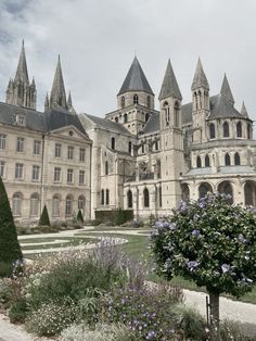 an old building with towers and flowers in the foreground