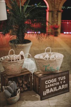 two baskets with balls in them sitting on top of wooden crates next to a palm tree