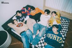 group of young men laying on top of a bed