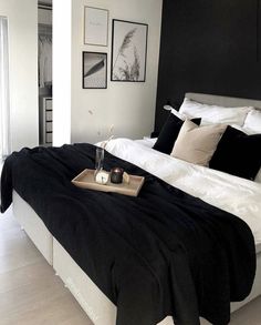 a black and white bedroom with pictures on the wall above the bed, along with a tray full of candles