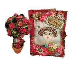 a small potted plant next to a card with a picture on it and flowers