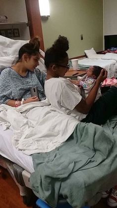 two women and a baby laying in a hospital bed