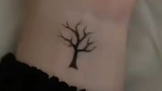 a small tree tattoo on the side of a woman's stomach is seen in this image