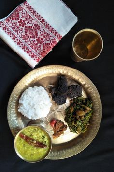 An Assamese style lunch platter served in bell metal utensils Page Cover Photo, Lunch Platter, Green Chilli Pickle, Malabar Spinach, Black Gram, Fiddlehead Ferns, Water Spinach, Pumpkin Flower