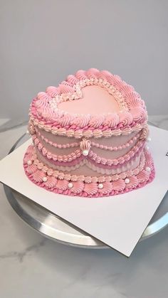 a pink heart shaped cake sitting on top of a plate