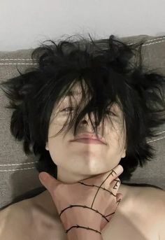 a man with black hair laying on top of a couch