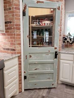 an old door is opened to reveal a pantry in the kitchen with white cabinets and brick walls