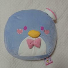 a blue stuffed animal with a bow tie on it's head and eyes, sitting on a white sheet