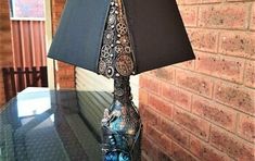 a lamp that is sitting on top of a glass table next to a brick wall