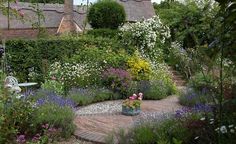 a garden filled with lots of different types of flowers and plants next to a building