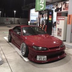 a red car parked in front of a gas station