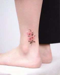 a woman's foot with a pink flower tattoo on the left side of her ankle