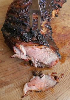 there is a fork in the meat on the cutting board with it's end cut off