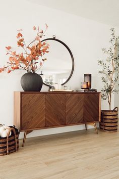 a living room with a large mirror and vases filled with flowers on top of a wooden cabinet