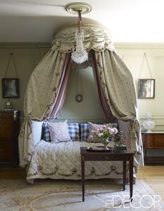 a canopy bed sitting in the middle of a living room next to a wooden table