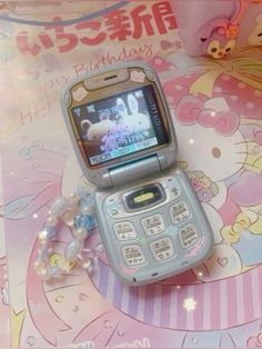 a cell phone sitting on top of a table next to a pink hello kitty sign