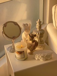 a white table topped with candles next to a mirror and vase on top of it