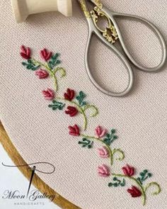 a pair of scissors sitting on top of a piece of embroidery