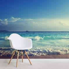 a white chair sitting on top of a wooden floor next to an ocean wall mural