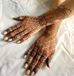 the hands and feet of a woman are decorated with henna designs on white fabric