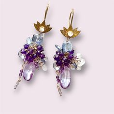 Beautiful Lotus and gemstone cluster earrings. Designed in monochromatic purple-violet color palette with complementing warm gold tones, these charming earrings exude a sense of mystical romance and delicacy at the same time. Suspended from lotus shaped 18k gold vermeil over sterling silver earwires featuring a fire moonstone setting, variety of faceted and smooth gemstones reflect light with your every move: faceted mystic Quartz cube beads in pale blue-violet, faceted dark purple African ameth Luxury Purple Multi-stone Earrings, Amethyst Multi-stone Briolette Earrings, Lavender Amethyst Earrings With Gemstone Accents, Violet Color Palette, Romantic Woman, Mystic Quartz, Beaded Earrings Diy, Cube Beads, Violet Color