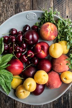 a white bowl filled with lots of different types of fruit on top of a wooden table