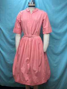 "1950s W:28 Vintage 50s NPC Fashions Cotton Shirtdress fit and flare short sleeve cotton button up Peter Pan collar matching belt pleated  Vintage 50s fit and flare classic pullover style shirt dress. Under vintage label NPC Fashions. Solid cotton in nice popsicle pink blush color. V neck with a  Peter Pan collar. Mother of pearl shank buttons. Photographed on fit form size 2, please check measurements. Matching belt. Pleated skirt. Added petticoat not included.  MEASUREMENTS  Bust: 38\" Waist: 28\" Hips: free Bodice length: 17\" Skirt length: 24\"  Length: 41\" with 1\" hem available to let down Sleeve: 12\" This is in good vintage condition, presents beautifully and is completely wearable as is! ✨" Classic Pleated Short Sleeve Shirt Dress, Classic Pleated Shirt Dress With Short Sleeves, Pink Short Sleeve Shirt Dress For Daywear, Fitted Short Sleeve Shirt Dress With Pleated Waist, Short Sleeve Shirt Dress With Pleated Waist, Short Sleeve Shirt Dress With Pleated Waist For Daywear, 1950s Style Short Sleeve Day Dresses, 1950s Style Short Sleeve Dresses For Daywear, Classic Belted Short Sleeve Shirt Dress