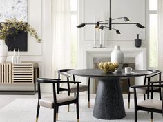 a dining room table with chairs and a vase on it in front of a fireplace