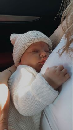 a baby sleeping in the back seat of a car wearing a white knitted hat