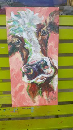 a painting of a cow on a green bench