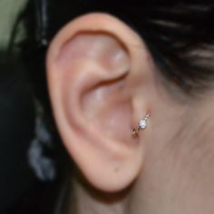 a woman's ear with a single diamond in it