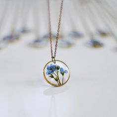 Unique handmade necklace features a twig of real preserved Forget-me-nots. Counted among the tiniest of flowers with the most soothing shade of blue, these beautiful blossoms come with numerous interesting legends and historical significance. And as the name suggests, they are given or used to decorate gifts with the hope the recipient will not forget the giver. It commonly symbolizes faithful love and memories and friendship. Pure brass circle measures approx. 0.7 inches (2 cm) in diameter and Blue Flower Jewelry With Natural Inclusions, Delicate Blue Jewelry With Pressed Flowers, Blue Nature-inspired Round Pendant Necklace, Vintage Birth Flower Necklaces For Jewelry Making, Vintage Necklaces With Pressed Flowers For Jewelry Making, Blue Handmade Botanical Jewelry, Blue Round Pendant Necklace With Pressed Flowers, Delicate Blue Birth Flower Necklace, Delicate Blue Necklace With Birth Flower