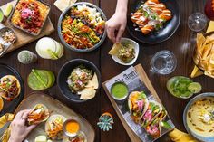 people eating mexican food at a table with plates and bowls on it, including guacamole