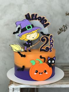 there is a halloween cake with two pumpkins on the top and a witch hat