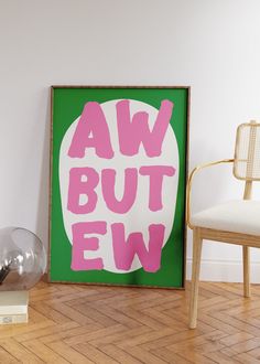 a green and pink poster sitting on top of a wooden floor next to a chair