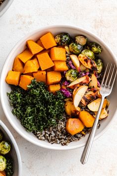 two bowls filled with different types of food next to silver utensils on a table